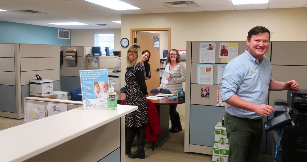 A welcoming group photo of the Family Tree Home Care team inside their office. The employees are all smiling warmly and looking at the camera, reflecting their friendly and compassionate approach to home care services.